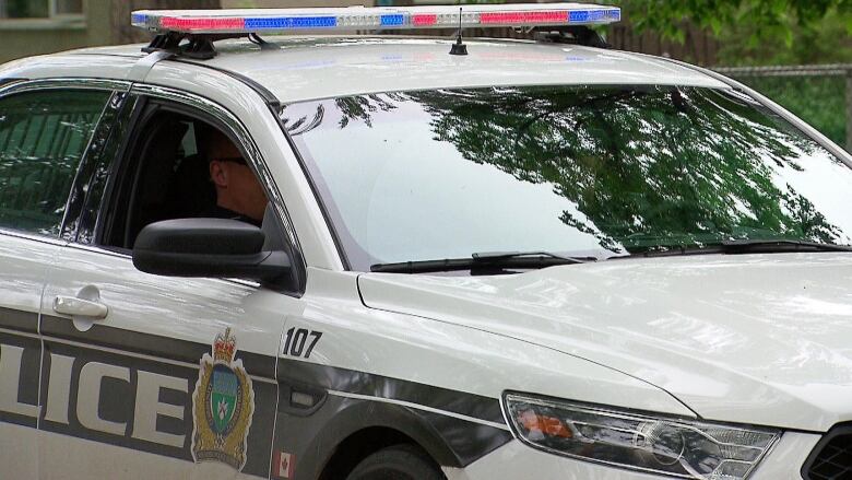 A Winnipeg Police Service car is seen parked under trees.