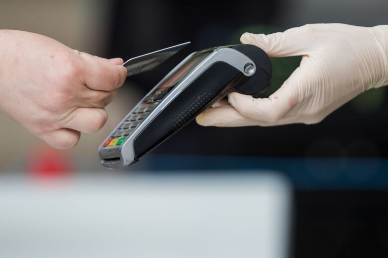 A person taps a bank card on a payment terminal to make a contactless payment.