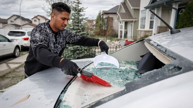 Sukh Singh, 22, sweeps up broken glass from his car on June 14, 2020.