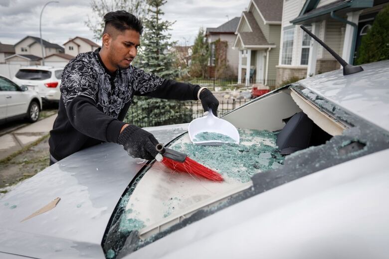 Sukh Singh, 22, sweeps up broken glass from his car on June 14, 2020.