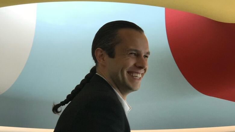 A man wearing a suit smiles for the camera towards the right frame.