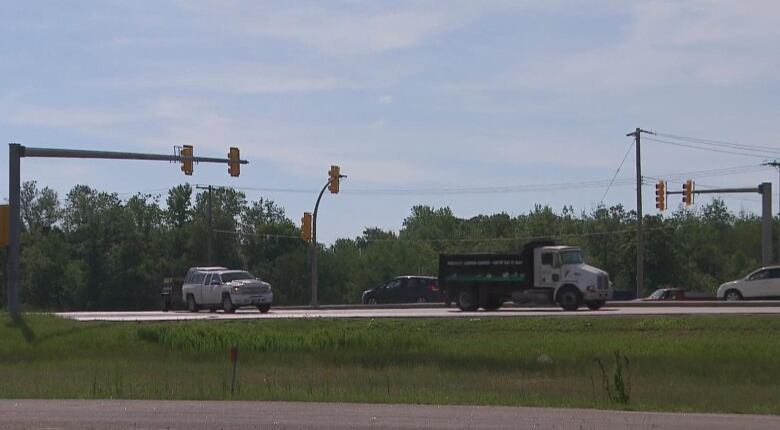 Vehicles drive past traffic lights at a highway intersection.