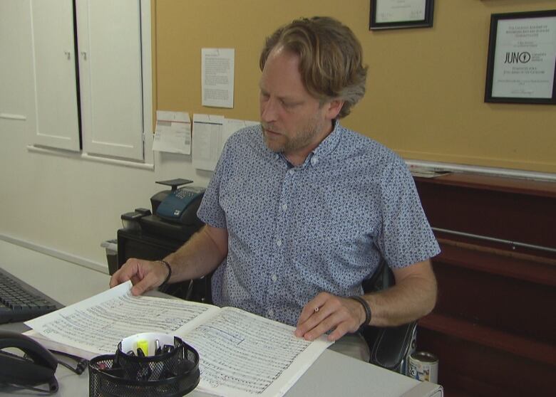 Mark Vuorinen the artistic director of the Grand Philharmonic Choir sits at his desk going through notes.