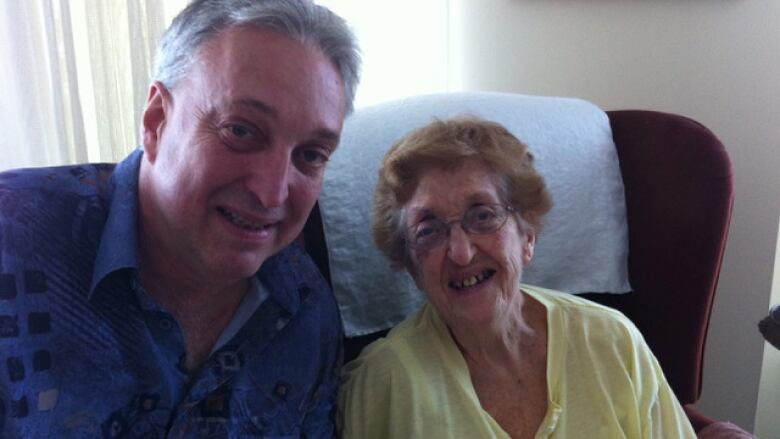 A portrait of a man and an elderly woman. Both are smiling at the camera.