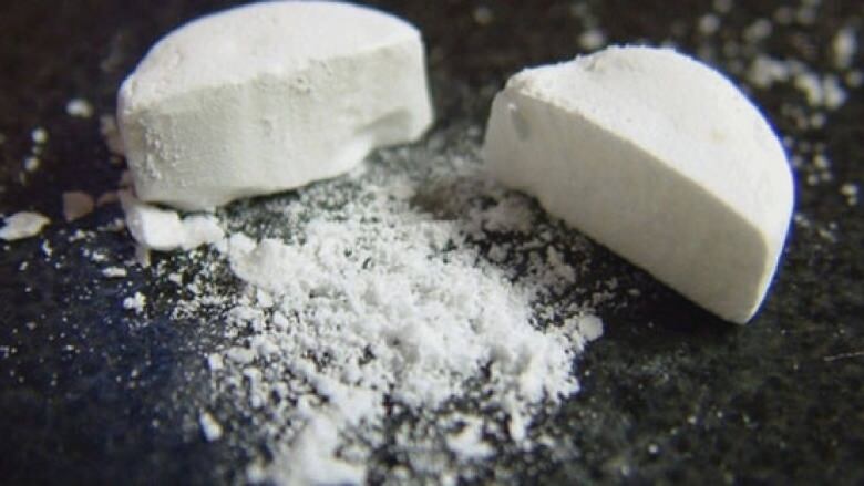 A close up picture of fentanyl tablet split in half with powder showing.