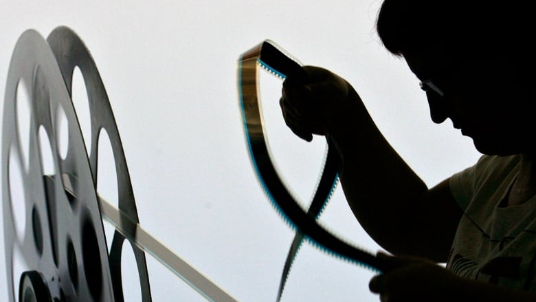  A worker prepares a cinema reel to be displayed.