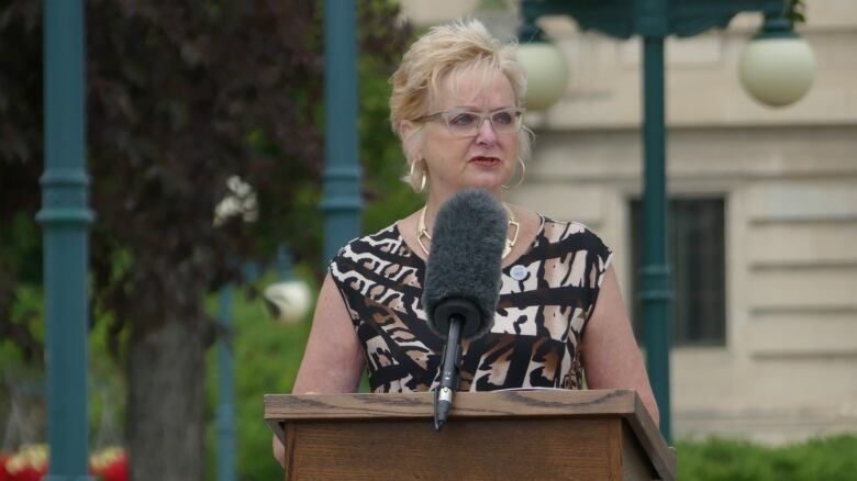 A woman stands behind a microphone.