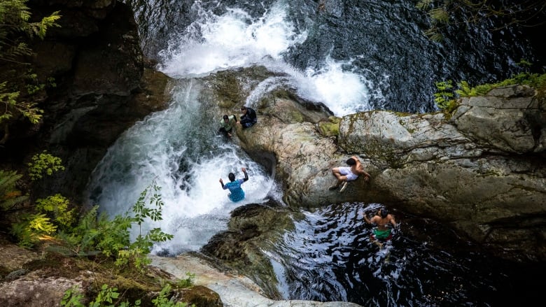 Teenagers jump into the water at Lynn Canyon Park.