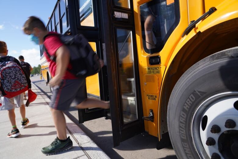 A child steps off a yellow school bus.