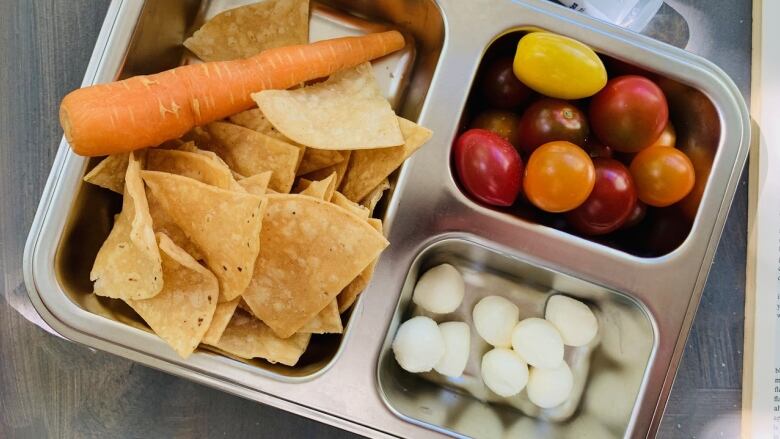 A sectioned metal tray with chips, carrots, cherry tomatoes and cheese