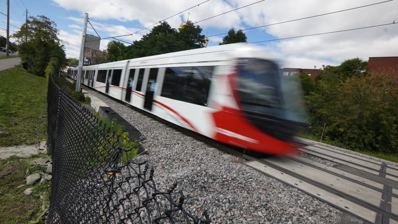 A red and white train speeds along a rail line.