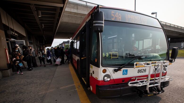 A bus at a stop, with passengers boarding.