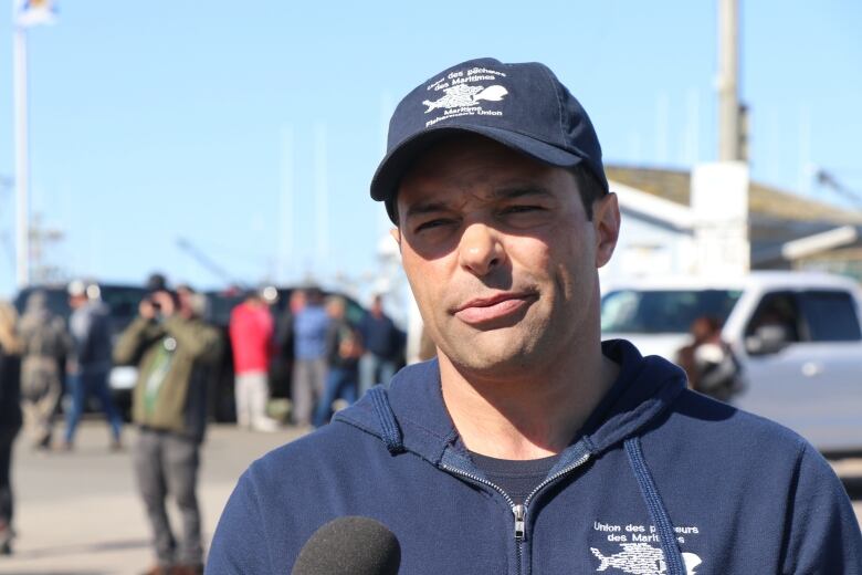 A man in a zip up sweater and ball cap