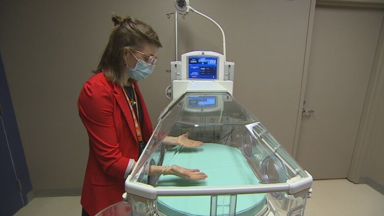 Woman at side of bed that can weigh babies. 