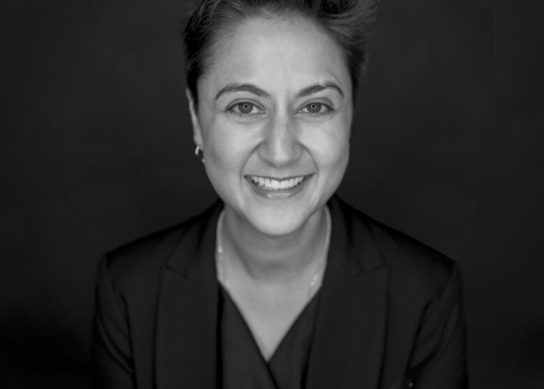 A woman with short hair smiles at the camera in this black and white portrait.