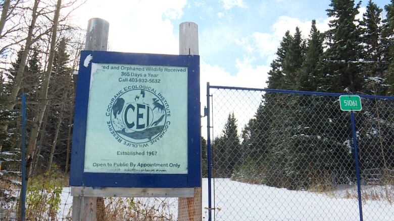 A sign at a snow-clad location with trees.