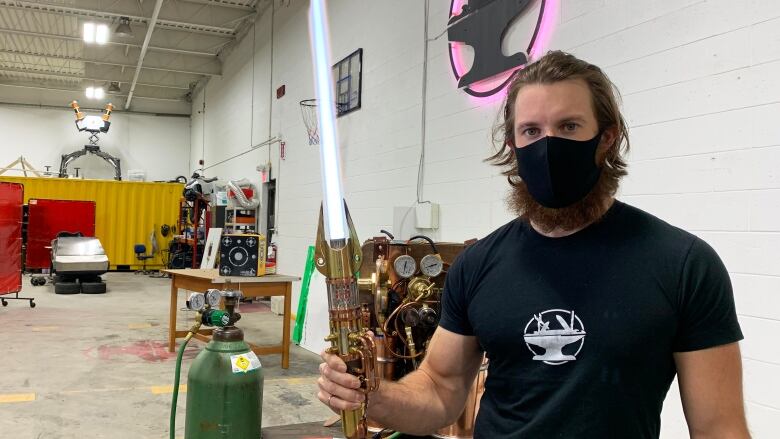 A man holds up a purple sword that looks like the blade is a light