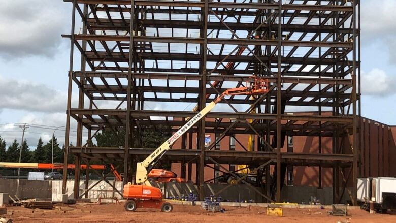 A steel-girdered building under construction with crane in the foreground.