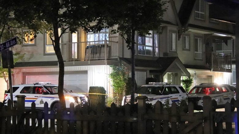 A townhouse complex is seen with police cars surrounding it.