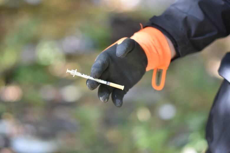 A gloved hand, holding a needle.