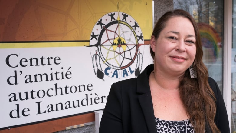 A woman stands in front of a sign that reads Centre d'amitie autochtone de Lanaudiere. 