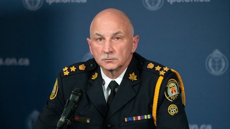 A man in a police uniform sitting behind a microphone.