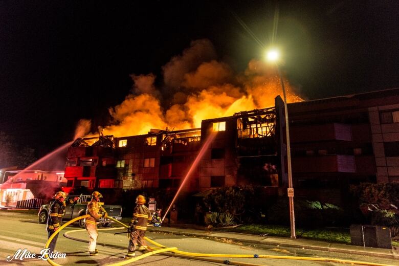 Three fire fighters use hoses to spray a stream of water onto a fire in the roof of an apartment complex in Penticton, B.C. 