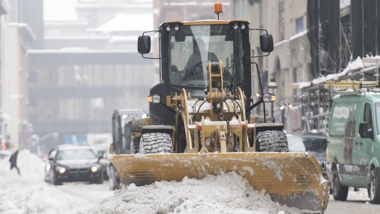 A snowplow pushing snow on the street. 