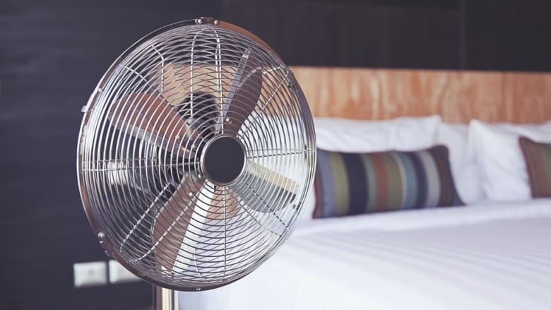 Metal cooling fan on stand in bedroom.