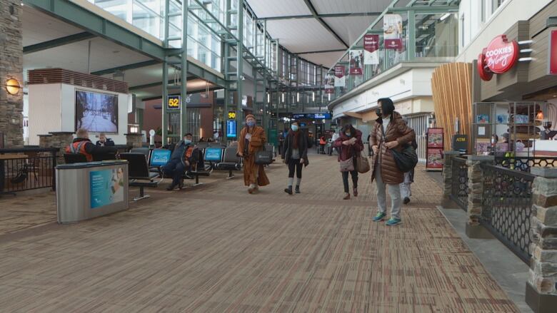 People walk inside a large airport terminal.