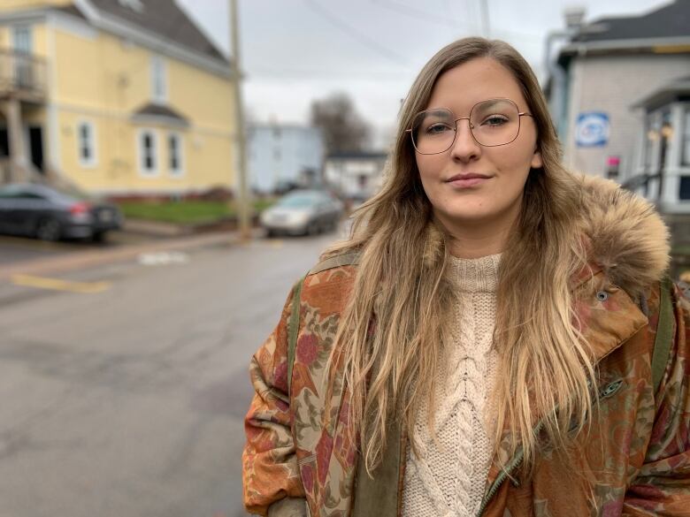 A woman stands in front of a city street.