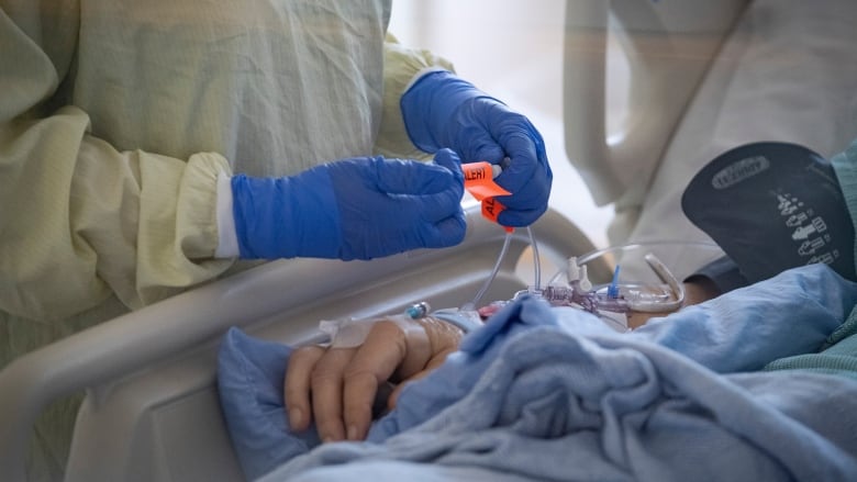 A nurse tends to a patient suspected of having COVID-19 in an intensive care unit.