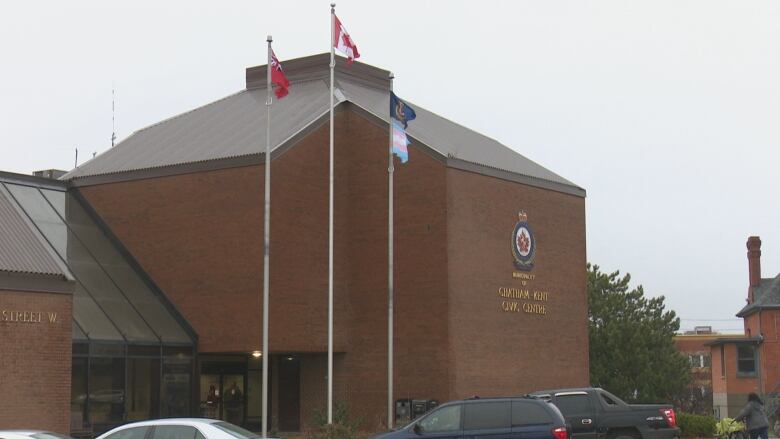 A brown building with flag poles in the front