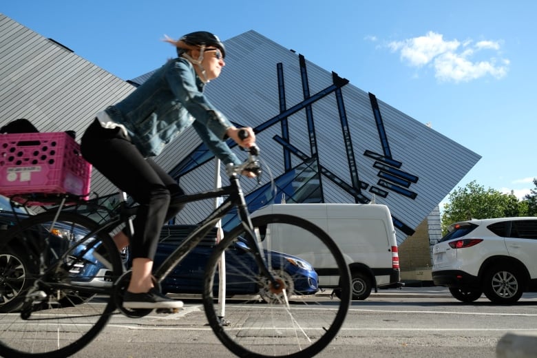 A woman cycles past the Royal Ontario Museum in a protected bike lane on Bloor Street West.