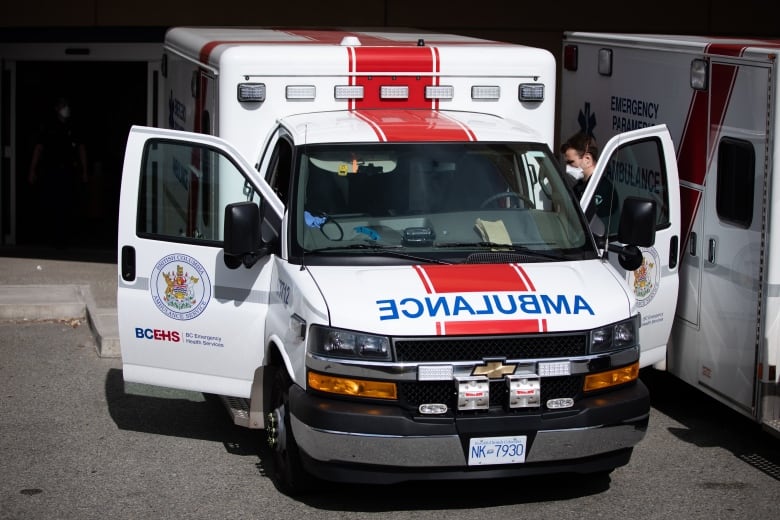 A paramedic is seen getting into a parked B.C. ambulance that has both doors open.