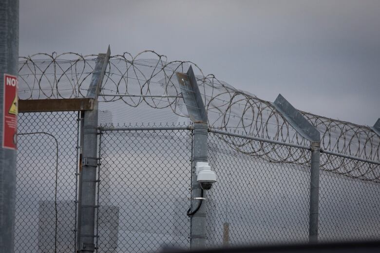 A fence with barbed wire and a security camera. 