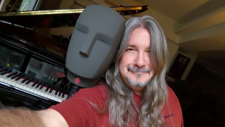 A man takes a selfie in front of a piano.