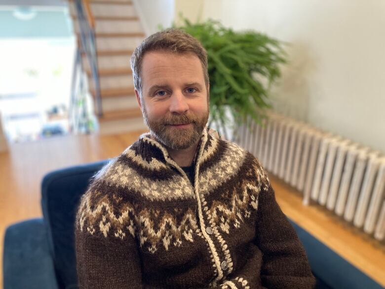 A man with brown hair and a beard wearing a brown fuzzy sweater