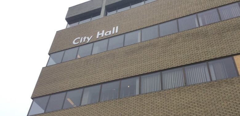 A tall office building with the words 'City Hall' on it.