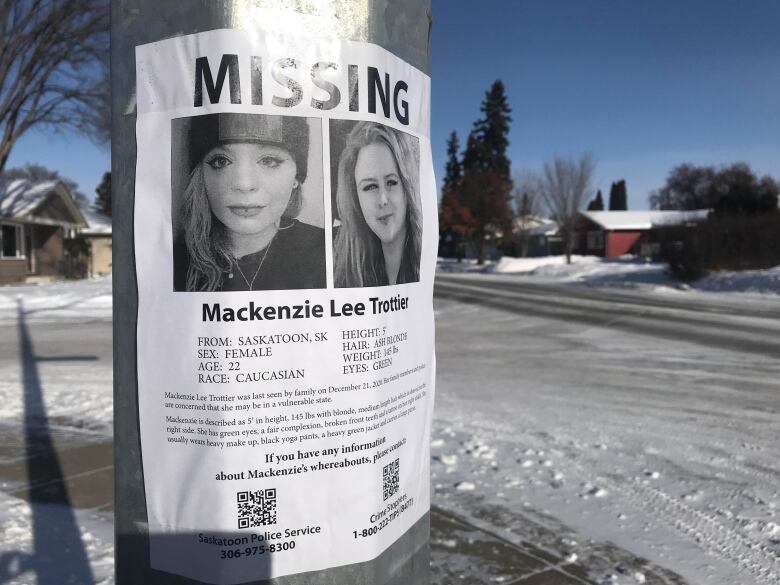 A poster taped to a light post shows two images of a young woman. It's text includes the word 