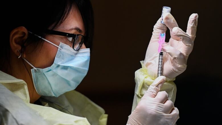 Francesca Passer, a registered pharmacist technician, prepares a dose of the Pfizer-BioNTech COVID-19 vaccine at a vaccination clinic in Toronto. 