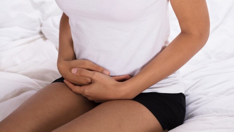 A woman clutches her abdomen 