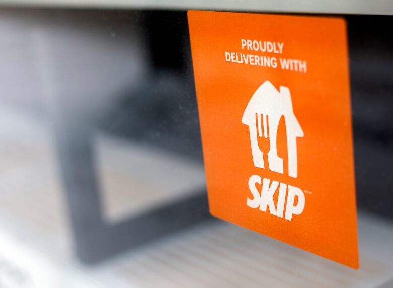 Orange sign plastered on a window reads Skip the Dishes