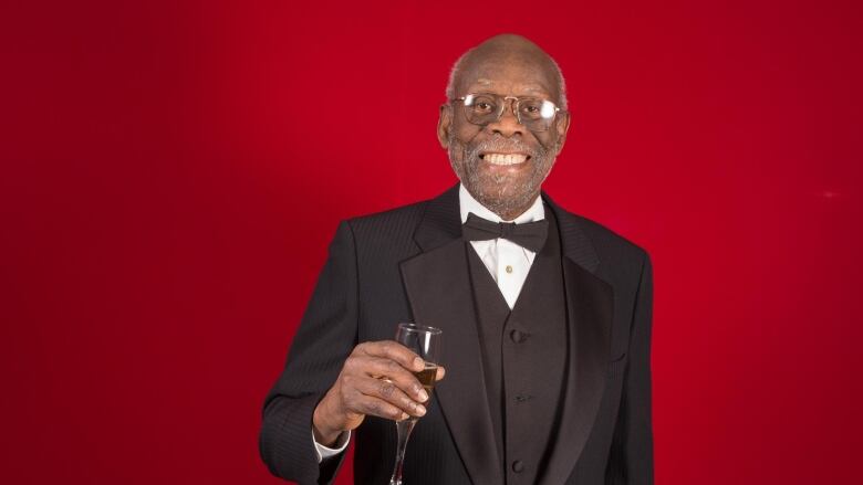 Man holding glass in celebration in suit.