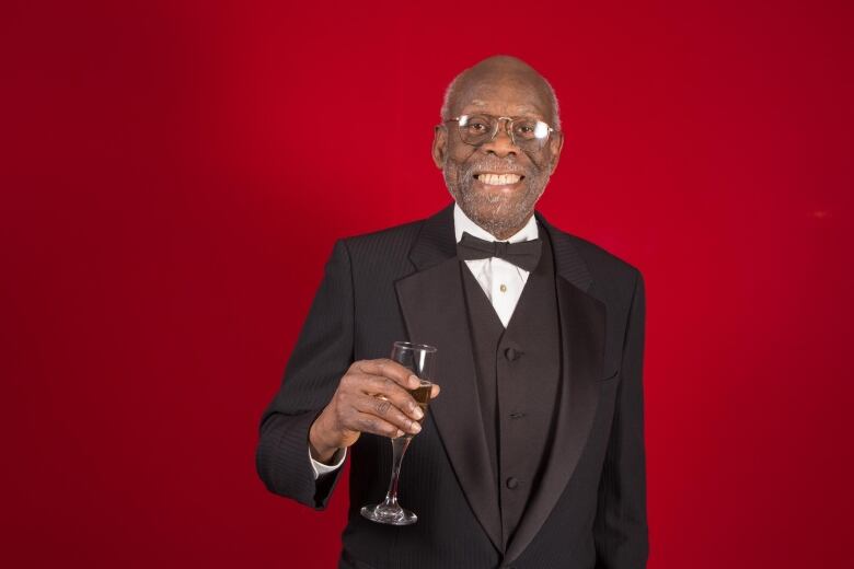 Man holding glass in celebration in suit.