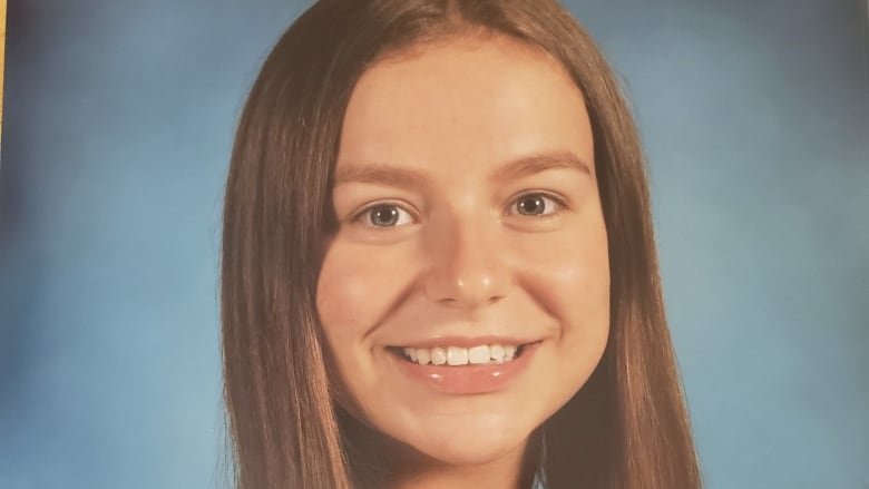 A teenager girl smiles in a school portrait. 