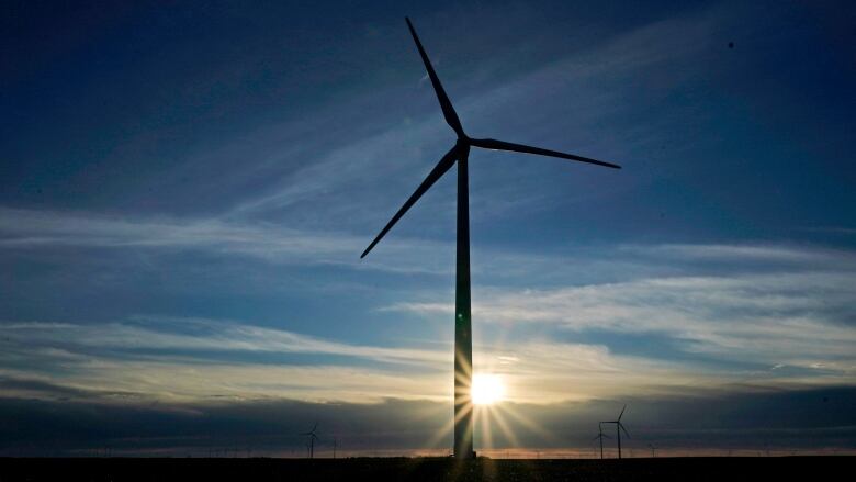 A windmill is seen against a background of the setting sun.