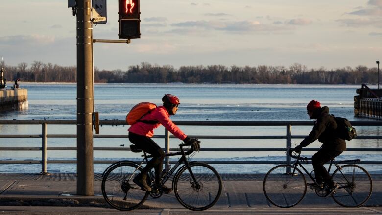 Two cyclists riding in front of Lake Ontario.