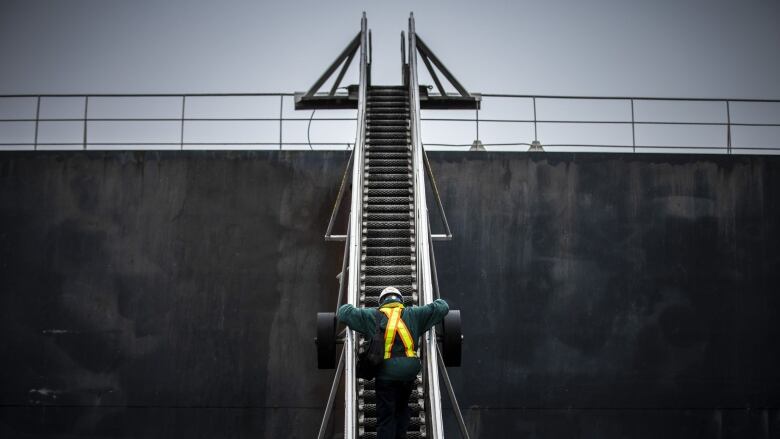 a person in a safety vest climbs up steps to a ship