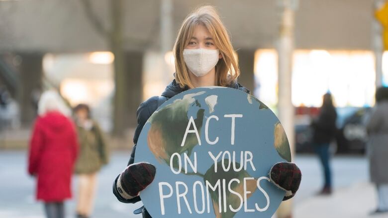 A youth climate protester with a decorated sign standsat the Queen Street West and Bay Street intersection in downtown Toronto onFriday, March 19, 2021.